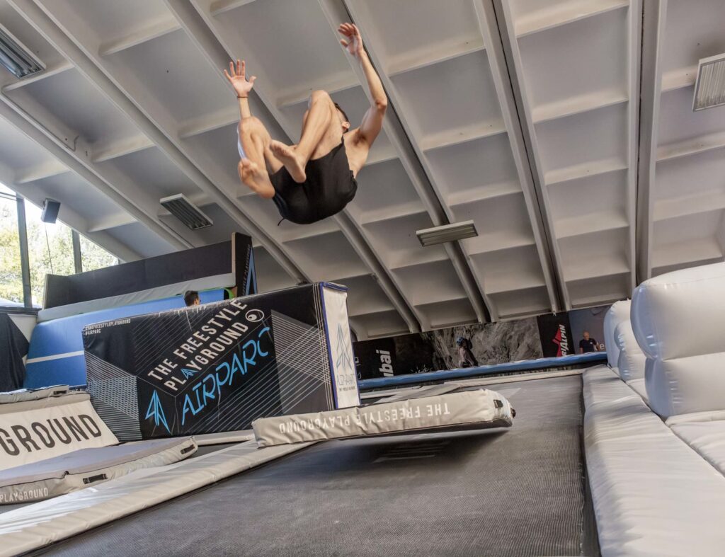 Un atleta raccolto in aria, a metà di un salto all'indietro sul trampolino dell'Airparc
